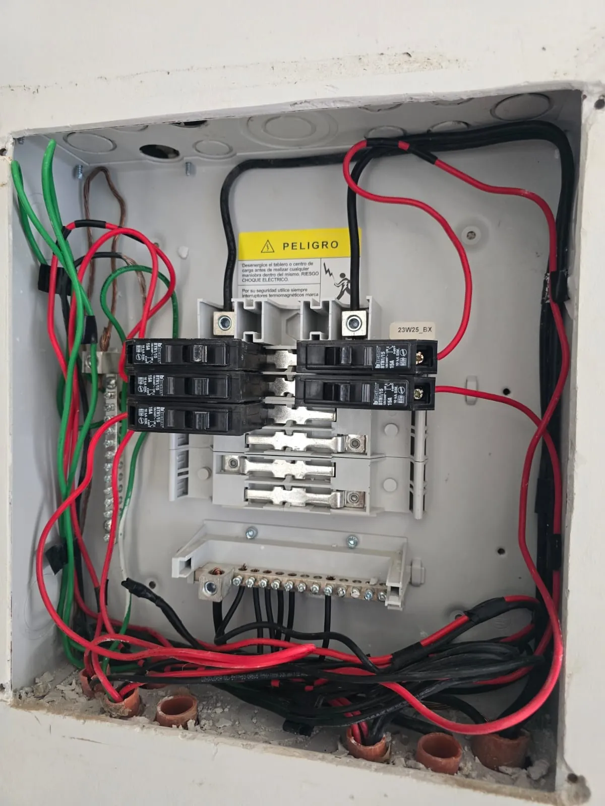 Centro de carga eléctrico abierto mostrando conductores mal conectados